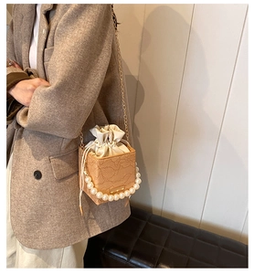 Detail of lace embossed bucket bag with large pearl handle and metal chain strap