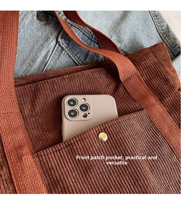 Close-up of brown corduroy tote bag showing front pocket with gold button and thick strap