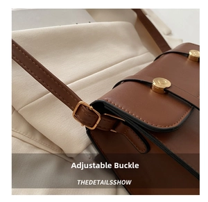 Detail of adjustable golden buckle and premium brown leather texture on handbag