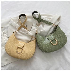 Detail of crocodile pattern faux leather underarm bags in cream and sage green with pearls