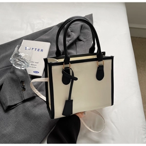 Detail of a minimalist cream and black tote bag with handle and adjustable strap