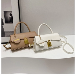 Detail of light brown and white crossbody bags with gold locks on a display stand
