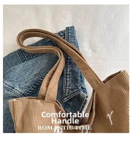 Detail of brown corduroy tote bag with white letter embroidery and thick handles