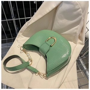 Detail of mint green crocodile pattern faux leather handbag with pearl handle and gold buckle
