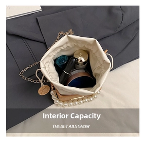 Interior capacity of cream bucket bag with cosmetics, pearl handle and gold chain details