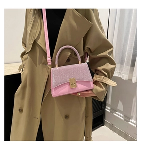 Detail of pink sequin crossbody bag with golden metal turn-lock and leather handle