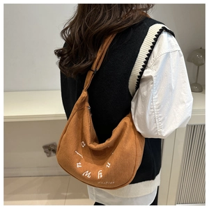 Detail of caramel corduroy crescent bag featuring white embroidery and adjustable strap