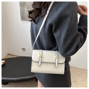 Vue détaillée du sac à bandoulière blanc crème avec boucles dorées et bords noirs