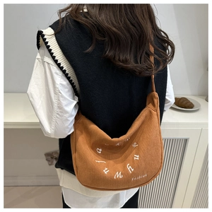 Detailed close-up of a caramel corduroy half-moon tote bag with white letter embroidery