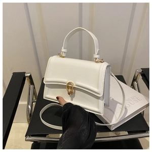 Dettaglio della borsa strutturata bianca con fibbia dorata su sedia di design elegante