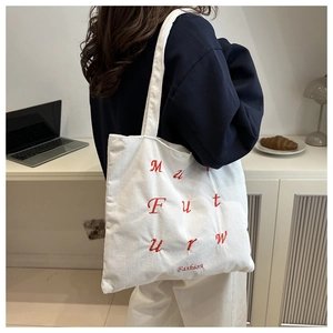 Gros plan du sac cabas en velours côtelé blanc avec broderie de lettres rouges mode