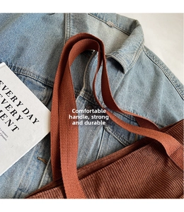 Close-up of durable woven handles on a brown corduroy tote bag with vintage texture
