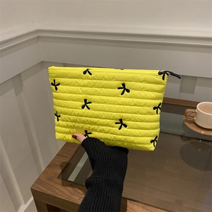 Trousse à maquillage matelassée en velours côtelé avec broderie papillon tenue à la main