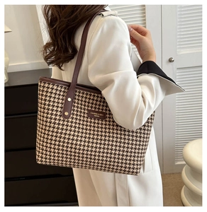 Dettaglio borsa shopper pied-de-poule marrone con tracolla in pelle su blazer bianco