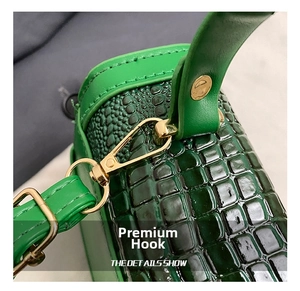 Detail view showing golden metal hardware and green crocodile texture on a leather bag
