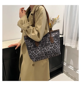 Detail view of leopard print tote bag with brown leather handles worn with a trench coat