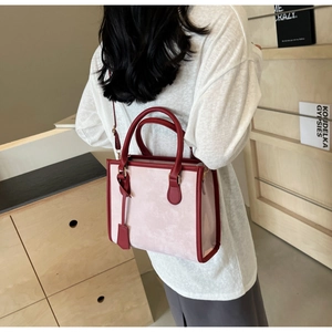 Detail of elegant pink and burgundy tote bag worn by model in minimalist indoor setting