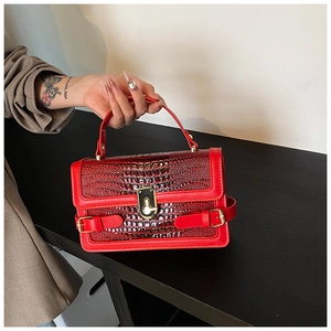 Detail of red crocodile pattern handbag featuring a gold lock and premium texture