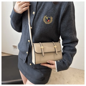 Détail d'un sac à bandoulière rectangulaire en cuir beige avec finitions dorées chic