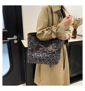 Close-up of leopard print tote bag with brown leather handles worn over a trench coat