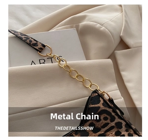 Close-up of golden metal chain link and leopard print strap on crescent shoulder bag