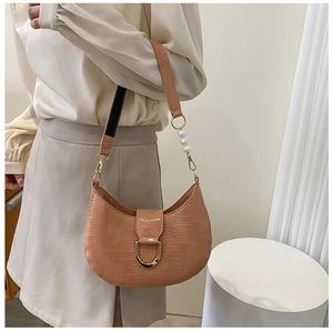 Detail of caramel crocodile pattern shoulder bag with pearls and golden D-ring hardware