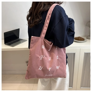 Detail of pink corduroy tote bag showing high-quality embroidered letters and soft texture