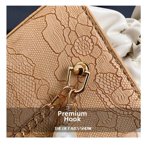 Detailed close-up of beige lace texture, golden hook, and white pearl pendant on a bag