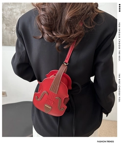 Detail of creative violin-shaped red crossbody bag worn over a black blazer for women