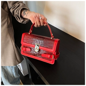 Detail of red crocodile texture PU leather handbag featuring a shiny finish and gold lock