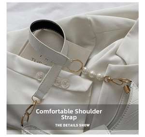 Detail view of white crocodile pattern shoulder bag with pearl accents and gold metal buckle