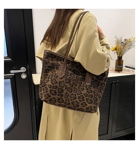 Detail of leopard print tote bag with brown leather handles worn with a beige trench coat