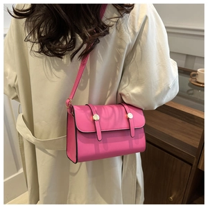 Model wearing vibrant pink rectangular crossbody bag over a beige trench coat