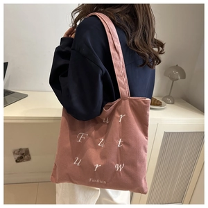 Detailed texture of pink corduroy tote bag with white letter embroidery for daily wear