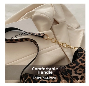 Detail of leopard print crescent bag with gold chain strap on a beige blazer