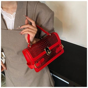 Detail of red crocodile pattern handbag with gold hardware and stylish turn-lock closure