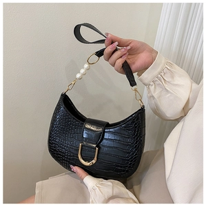 Detail of black crocodile texture bag with gold D-ring and large pearl chain accents
