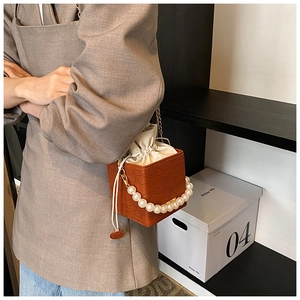 Detail of lace embossed leather bucket bag with elegant pearl handle and drawstring pouch