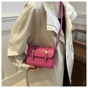Détail du sac bandoulière rose fushia avec boucles dorées porté sur un manteau beige