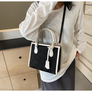 Detail of a chic black and white tote bag shown with an adjustable shoulder strap