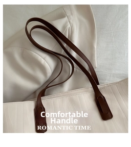Detail of brown leather handles and 3D wavy textured fabric on cream tote bag
