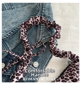 Detail of leopard print handbag featuring a trendy scrunchie handle and secure metal zipper