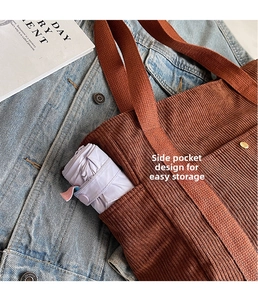 Detail of a brown corduroy tote bag showing a side pocket holding a purple umbrella