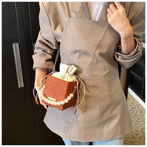 Detail of vintage lace bucket bag with pearl handle and drawstring closure in warm brown