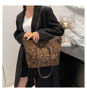 Detail view of large leopard print tote bag with brown leather handles and shoulder strap