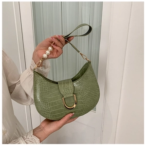 Detail of green crocodile embossed crescent bag with elegant pearl strap and gold hardware
