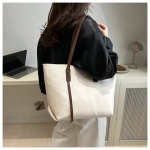 Large white tote bag with brown leather straps shown in a minimalist office setting