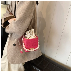 Detail of fuchsia lace bucket bag featuring pearl handle and satin drawstring closure