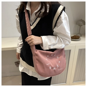 Close-up of pink corduroy tote bag with circular letter embroidery on a female model