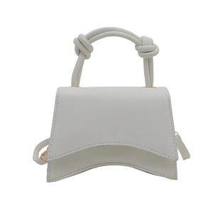 Chic white hourglass handbag with a knotted top handle and adjustable shoulder strap
